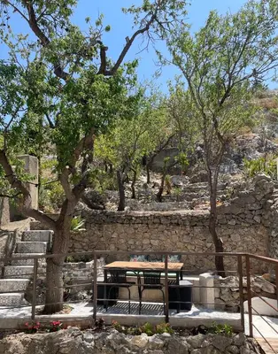 a picnic table with a bench next to a stone wall at Appartement standing proche plage in Fitou