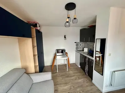 a living room with a couch and a kitchen at Superbe Studio avec vue sur le port de Gruissan, piscine, parking in Gruissan