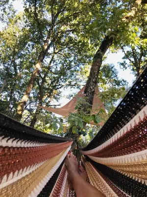 a person holding a hammock in front of trees at Ô cocon del Lauragués in Ricaud