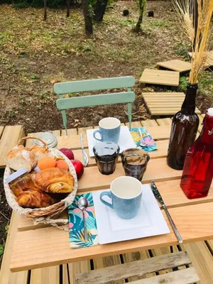 a picnic table with a basket of bread and cups at Ô cocon del Lauragués in Ricaud