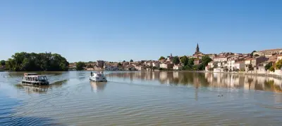 two boats on a river with a town in the background at Ô cocon del Lauragués in Ricaud