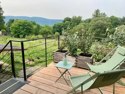 a deck with two chairs and a table on it at Séjour confort et nature in Saint-Amans-Valtoret