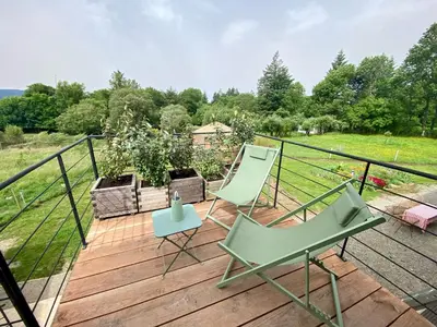 a deck with two chairs and a table at Séjour confort et nature in Saint-Amans-Valtoret