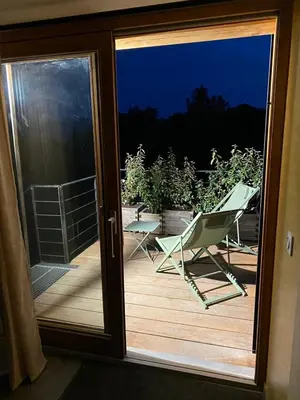 a sliding glass door with a chair on a deck at Séjour confort et nature in Saint-Amans-Valtoret