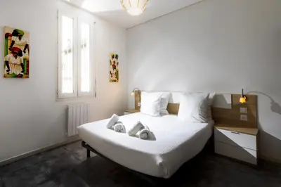 a bedroom with a bed with white sheets and a window at L'atelier De La Cite - Parking Gratuit Sécurisé in Carcassonne