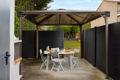a pergola with a table and chairs in a backyard at L'atelier De La Cite - Parking Gratuit Sécurisé in Carcassonne
