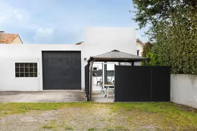 a white house with an open garage with an umbrella at L'atelier De La Cite - Parking Gratuit Sécurisé in Carcassonne