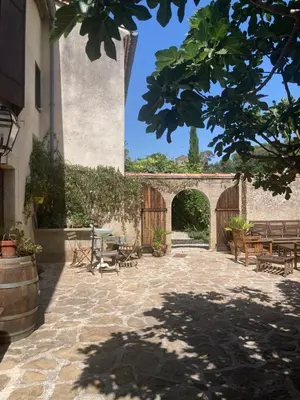 a courtyard with an archway and wooden tables and benches at ChezMathilde à LIMOUX in Limoux