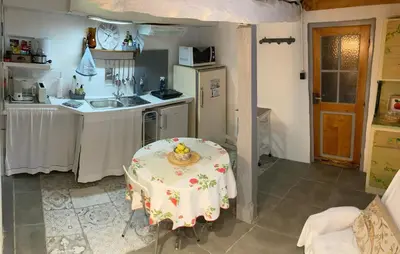 a small kitchen with a table and a refrigerator at ChezMathilde à LIMOUX in Limoux