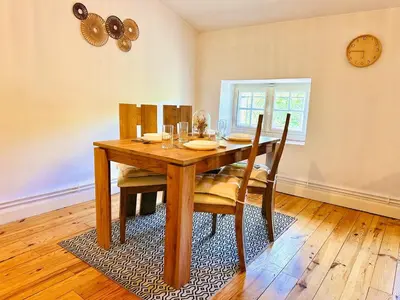 a dining room table with chairs and a clock on the wall at Le Charmant Boisé - T2 Centre Ville 7 min Cité Médiévale in Carcassonne
