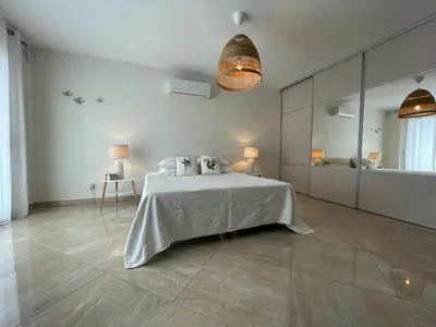 a white bedroom with a bed and a large mirror at La Villa des Cistes au calme vue Étangs in Narbonne