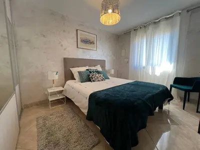 a bedroom with a large bed and a chandelier at La Villa des Cistes au calme vue Étangs in Narbonne