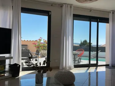 a living room with sliding glass doors with a view of a patio at La Villa des Cistes au calme vue Étangs in Narbonne