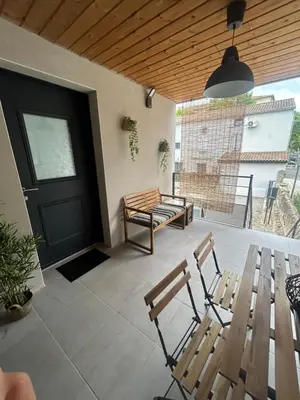 a patio with two wooden benches and a black door at Cocon chaleureux au coeur de Mirepoix in Mirepoix