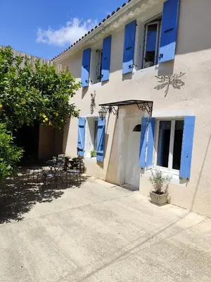 a building with blue shutters and tables and chairs at franck in Marcorignan
