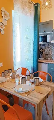 a wooden table with orange chairs and a kitchen at Perrutel - entre Bastide et cité in Carcassonne