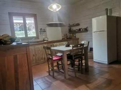 a kitchen with a table and chairs and a refrigerator at Maison chaleureuse en Ariège in Roquefort-les-Cascades