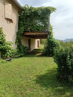 an ivy covered building with a balcony on the side of it at Maison chaleureuse en Ariège in Roquefort-les-Cascades