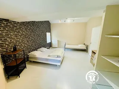 a room with two beds and a brick wall at Domaine 15 pers, Piscine, Pétanque, Canal du midi in Carcassonne
