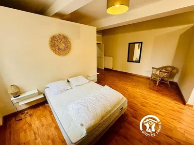 a bedroom with a bed and a wooden floor at Domaine 15 pers, Piscine, Pétanque, Canal du midi in Carcassonne