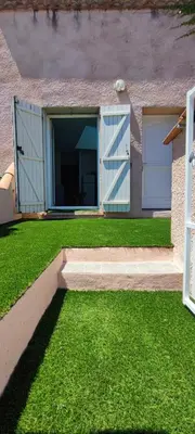 a house with two garage doors and green grass at Charmante maison in Carcassonne