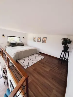 a white bedroom with a bed and a wooden floor at Cozy Tiny House plus SPA - à Pereille d'en Haut in Péreille