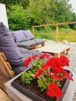 a couch and red flowers on a patio at Cozy Tiny House plus SPA - à Pereille d'en Haut in Péreille