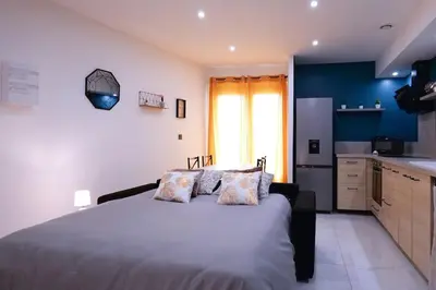 a bedroom with a large bed and a kitchen at Le Cocon Capestanais in Capestang