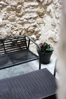 a black bench next to a stone wall with a plant at Le Cocon Capestanais in Capestang