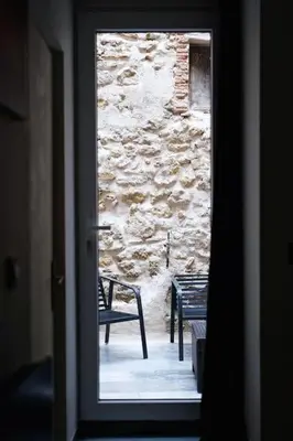 a door to a room with a bench and a stone wall at Le Cocon Capestanais in Capestang