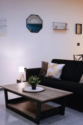 a living room with a black couch and a coffee table at Le Cocon Capestanais in Capestang