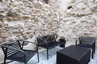 three black chairs and a table in front of a stone wall at Le Cocon Capestanais in Capestang