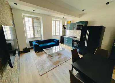 a living room with a blue couch and a kitchen at Good vibes in Limoux