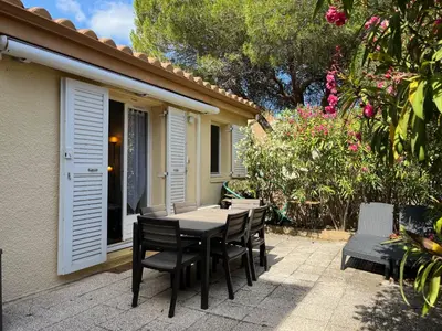 a table and chairs on a patio with flowers at Charmant T3 climatisé avec terrasse, proche plage & parking privé - 4/6 pers, Gruissan - FR-1-796-7 in Gruissan
