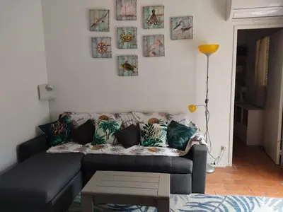 a living room with a couch and pictures on the wall at Charmant T3 climatisé avec terrasse, proche plage & parking privé - 4/6 pers, Gruissan - FR-1-796-7 in Gruissan