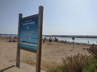 a sign on a beach with people on the beach at Charmant T3 climatisé avec terrasse, proche plage & parking privé - 4/6 pers, Gruissan - FR-1-796-7 in Gruissan
