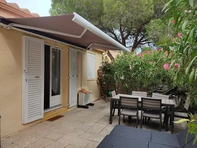 a patio with a table and chairs and flowers at Charmant T3 climatisé avec terrasse, proche plage & parking privé - 4/6 pers, Gruissan - FR-1-796-7 in Gruissan