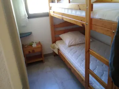 a bedroom with two bunk beds and a bed at T2 cabine climatisé avec piscine, parking privé, proche port et commerces, idéal 4-5 pers. - FR-1-796-9 in Gruissan