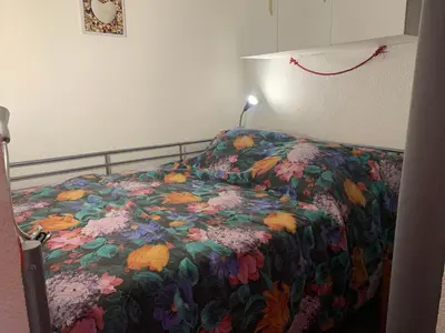 a bed with a floral comforter and a lamp at T2 cabine climatisé avec piscine, parking privé, proche port et commerces, idéal 4-5 pers. - FR-1-796-9 in Gruissan