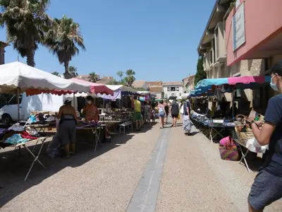 a group of people walking through an outdoor market at T2 cabine climatisé avec piscine, parking privé, proche port et commerces, idéal 4-5 pers. - FR-1-796-9 in Gruissan
