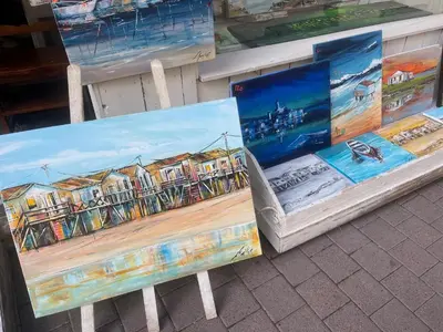a bench with paintings on it sitting on the street at **Gruissan : T2 cosy avec piscine, parking privé, proche plage et commerces** - FR-1-796-8 in Gruissan