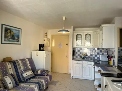 a living room with a couch and a kitchen at **Gruissan : T2 cosy avec piscine, parking privé, proche plage et commerces** - FR-1-796-8 in Gruissan