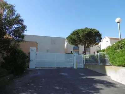 a gate in a driveway with a fence at **Gruissan : T2 cosy avec piscine, parking privé, proche plage et commerces** - FR-1-796-8 in Gruissan