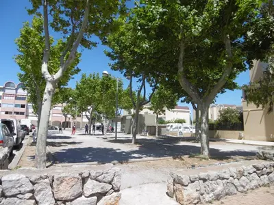 a street with trees and a stone wall at Gruissan - Studio rénové climatisé 2/3 pers, parking sécurisé, à 50m de la plage du Grazel - FR-1-796-16 in Gruissan