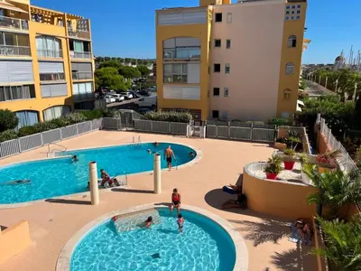 a pool at a resort with people in it at Gruissan: T3, 4 Pers, Piscine, Parking, Proche Commerce, Environnement Calme, Accès Plage - FR-1-796-14 in Gruissan