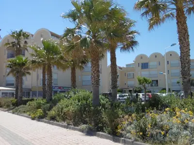 a row of palm trees in front of a building at Gruissan - À 2 Pas de la Plage - Studio Cabine pour 4 - Parking Sécurisé - FR-1-796-15 in Gruissan