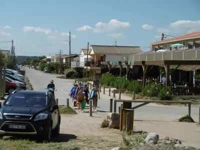 a group of people walking down a street with a car at T2 Confort Centre Port 4 Pers - Clim - Parking - Ascenseur - FR-1-796-25 in Gruissan