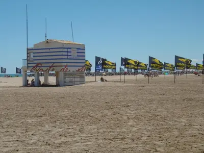 a building on the beach with people sitting on the sand at T2 Confort Centre Port 4 Pers - Clim - Parking - Ascenseur - FR-1-796-25 in Gruissan