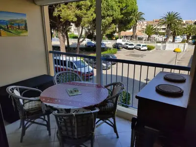 a table and chairs on a balcony with a view of a street at Studio spacieux à Gruissan - Parking - Vue port - Proche plage - FR-1-796-29 in Gruissan
