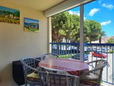 a table and chairs on a balcony with a view of a street at Studio spacieux à Gruissan - Parking - Vue port - Proche plage - FR-1-796-29 in Gruissan